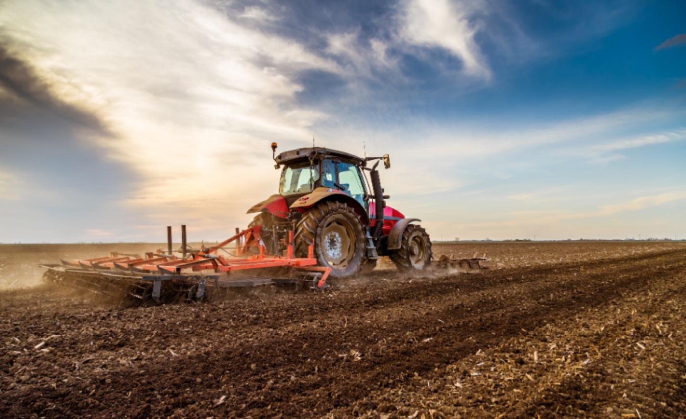 A farmer working the harvest with a tractor and grain cart, a partner of Sovereign Agricultural Group
