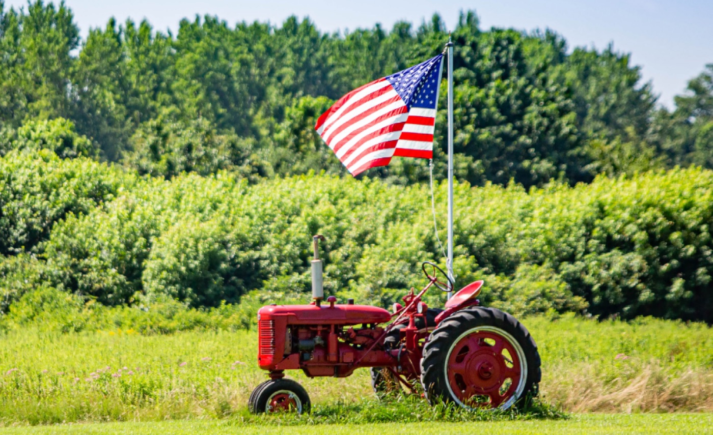 A tractor working a field at sunset, representing an established agricultural operation
